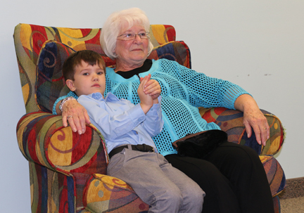Jonis Loney sits with his grandma, Jeanette Loney as his dad reads from the book.