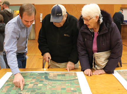 BluEarth Renewables representative, Jared Sproule shows county residents, Henry and Verna Willms the location on a map of one of the proposed projects.
