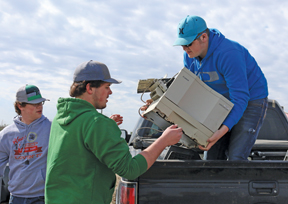 PHOTO BY JAMIE RIEGER- Kyle Crooymans, Mattias Crooymans, and Erik Bouw unload electronics at the landfill on Saturday. 