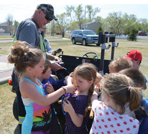 PHOTO BY TIM KALINOWSKI- CFB Suffield employee Cam Wiersma hands out rubber gloves and garbage bags to Ralston School students.