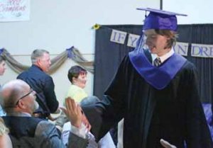 Photo by Jamie Rieger- Graduate Carter Thistlewaite gives a high-five as he leaves the stage at the end of the ceremony.