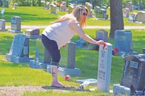 PHOTO BY TIM KALINOWSKI- Melissa Schaeffer places a poppy in memory of WW2 veteran Red Newnham, who passed away in 2015.