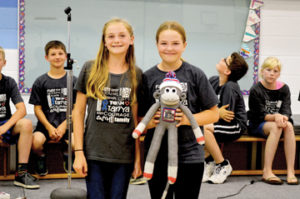 Photo by Tim Kalinowski- Evi Neubauer (left) presents "Thor the Monkey" to Jayla May to help raise awareness to the students' 1,000 T-shirts campaign. 