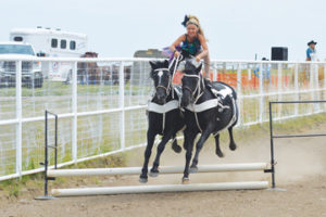 Photo by Tim Kalinowski- Cora Croteau of Young Gunz Trick Riders jumps her horses during the Roman riding demo.