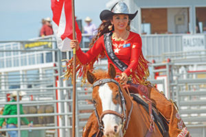 Photo by Tim Kalinowski- Medicine Hat Stampede Queen Brittney Chomistek rides in with the Canadian flag at the 37th annual Ralston Rodeo.