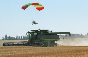 Photo By Jamie Rieger- Bert Schussler passes over this Shamrock Colony combine in his powered parachute.